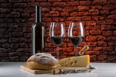 Close-up of wine bottles on table against brick wall