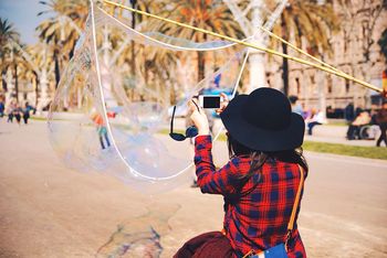 Rear view of woman photographing with mobile phone