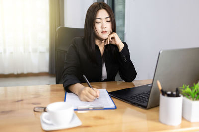 Young woman using phone while sitting on table