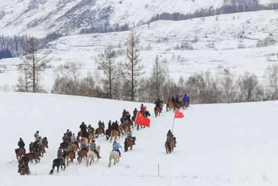 People riding horse on snow covered landscape