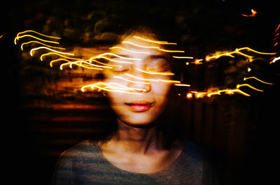 Digital composite image of young woman and light trails at night