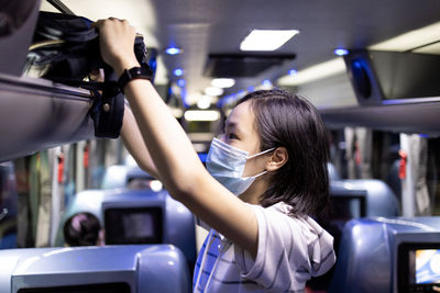 Midsection of woman photographing in bus