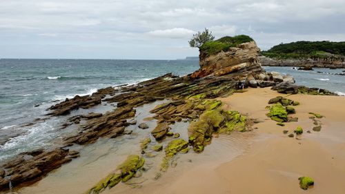 Rock formation on beach against sky