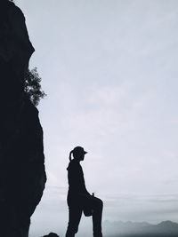 Silhouette man standing on rock against sky