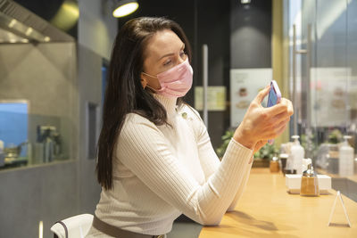 Portrait of young woman using mobile phone at cafe