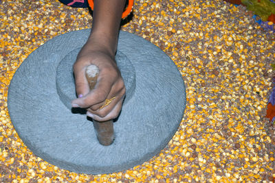 A village woman's hand, grinds gram in an old hand operated flour mill.