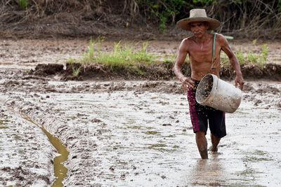 Shirtless man sowing seeds in farm