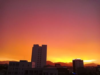 Silhouette buildings against orange sky