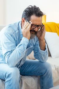 Portrait of young woman using mobile phone while sitting on sofa at home