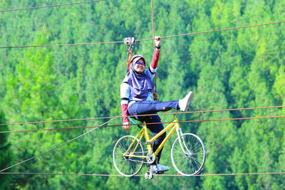 Full length of woman riding bicycle on rope