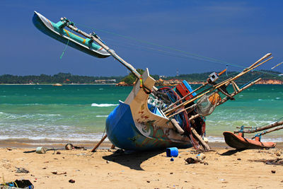 Fishing boat on beach against sky