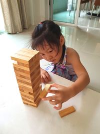 High angle view of girl playing with toy blocks on table at home