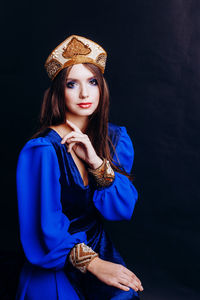 Portrait of beautiful woman in traditional clothing against black background