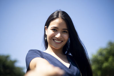 Portrait of a smiling young woman against blue sky