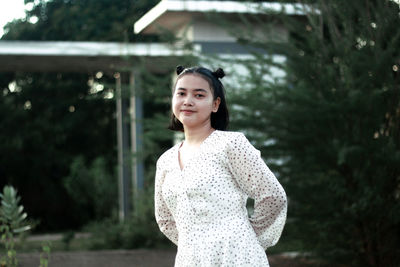 Portrait of young woman standing against trees