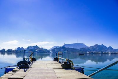 Sailboats moored in lake against blue sky