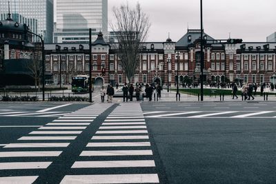 Group of people crossing road against buildings in city