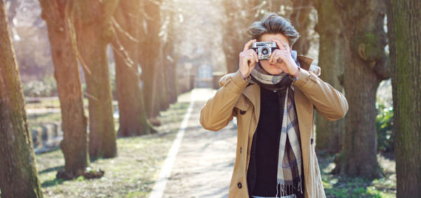 Young man photographing against trees