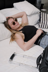 Woman with suitcase on bed in hotel having rest while traveling traveler with bag arriving at resort