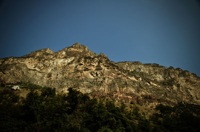 Low angle view of rock formation against clear blue sky