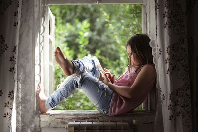 Kid girl on the box with the phone, the concept of sadness and loneliness, problems with gadgets