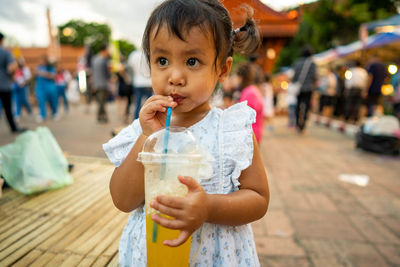 Cute girl drinking while standing outdoors