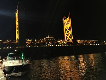 View of illuminated bridge over river at night