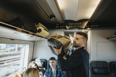 Man loading family's luggage on shelf in train