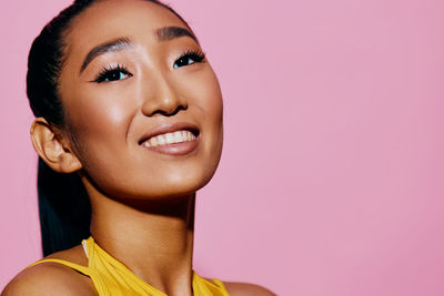 Close-up of young woman against pink background