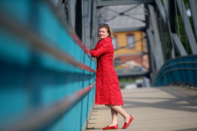 Full length of woman standing against red wall