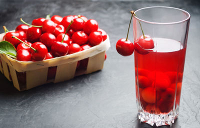 Juice or compote with cherries. fresh ripe red cherry in a basket on a gray concrete background