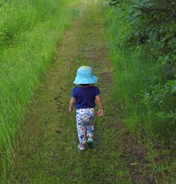 Rear view of girl walking on field