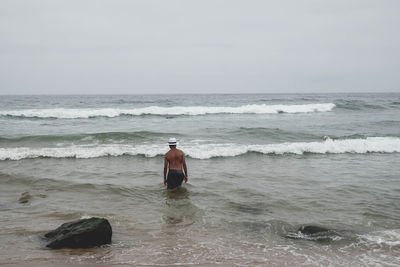 Rear view of man on beach against sky