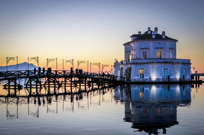 Reflection of building in lake against sky during sunset