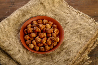 Hazelnuts in a clay plate on burlap on a wooden table. horizontal photo