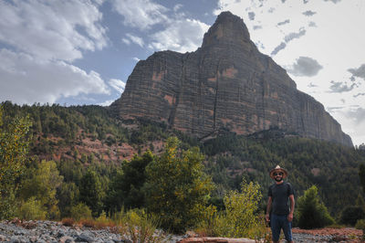 Full length of man standing on rock against sky