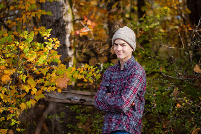 Smiling teen boy with arms crossed stands in woods, pacific northwest