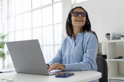 Woman using phone while sitting on table