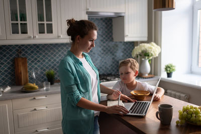 Boy drawing in notebook of working mother