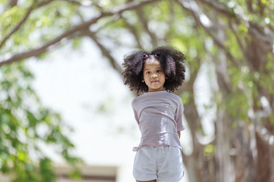 Portrait of girl standing against tree outdoors