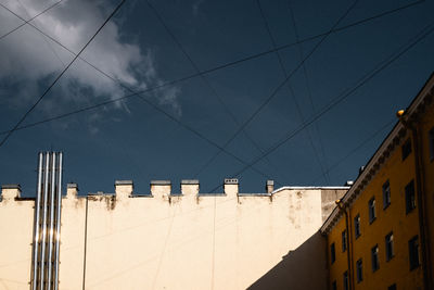 Low angle view of buildings against sky, covered with wires