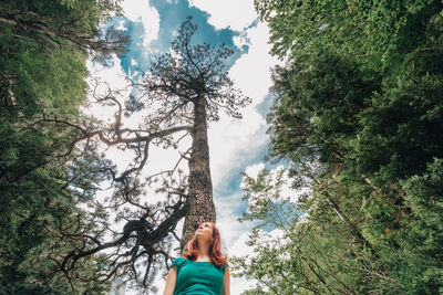 Low angle view of woman amidst trees against sky