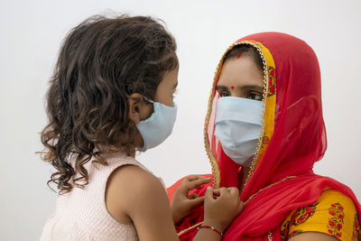 Cute girl wearing flu mask with mother against white background