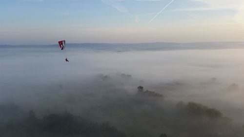 Person paragliding against sky during sunset