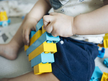 Midsection of boy playing with toy blocks