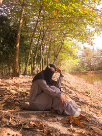 Woman sitting on tree in forest