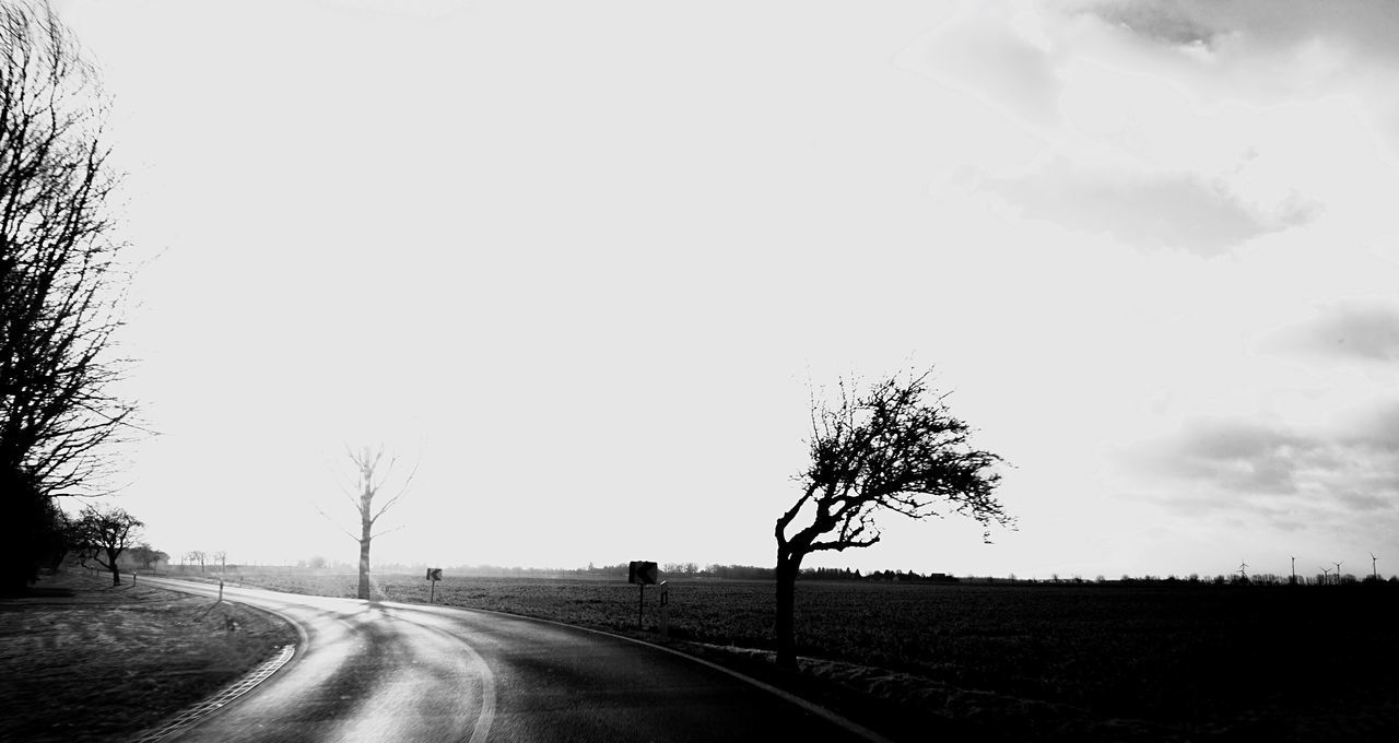 EMPTY ROAD BY FIELD AGAINST SKY