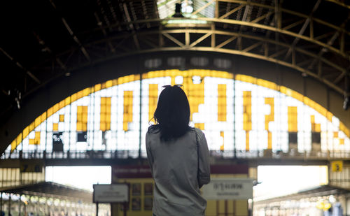 Rear view of woman standing at railroad station