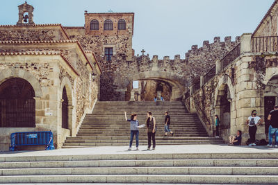 People on staircase of historic building against sky