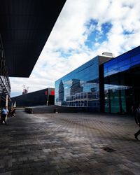 Modern buildings by street against sky in city